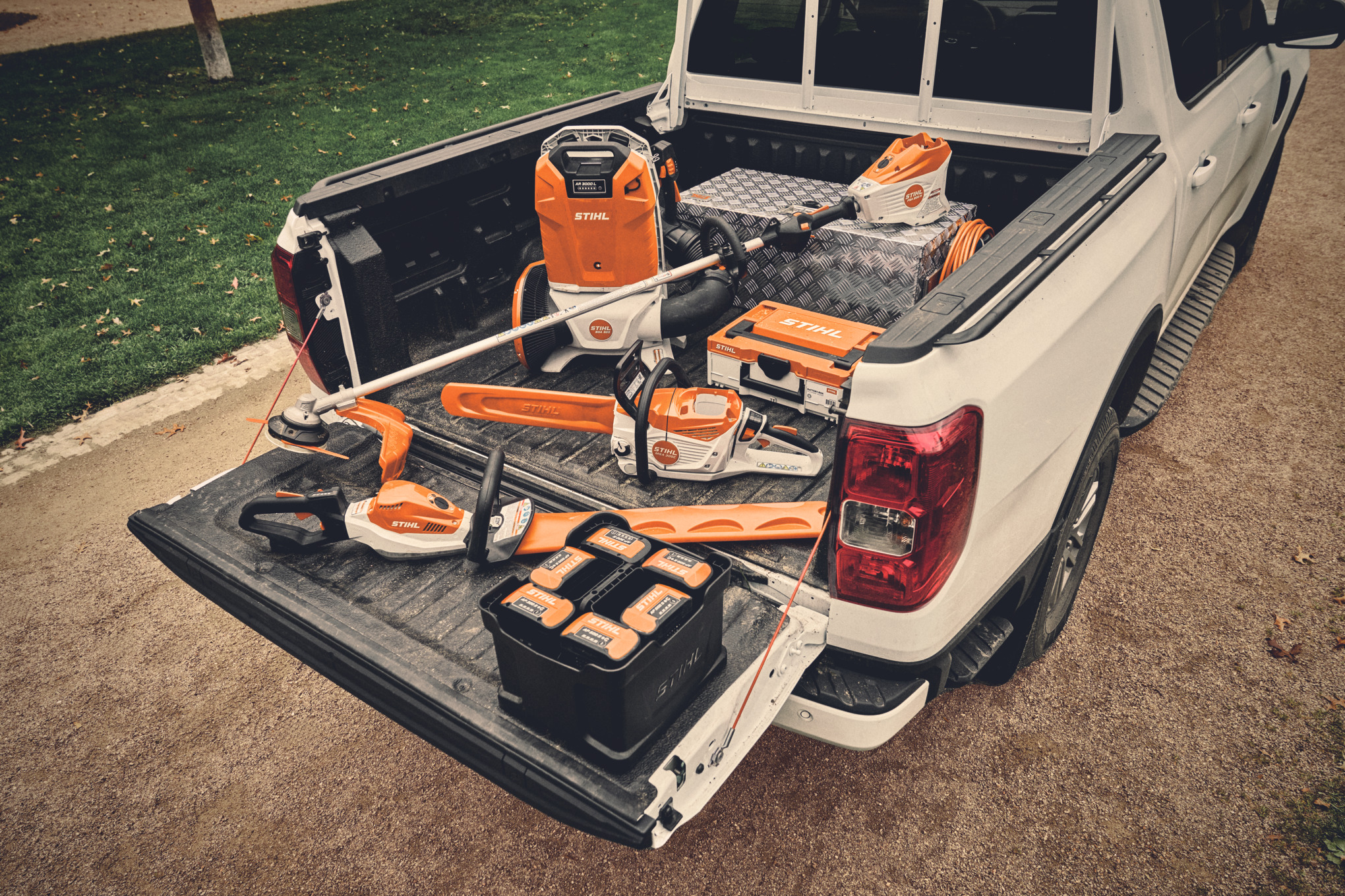 Várias ferramentas elétricas a bateria e as respetivas baterias do sistema STIHL AP na plataforma de carga de um veículo  