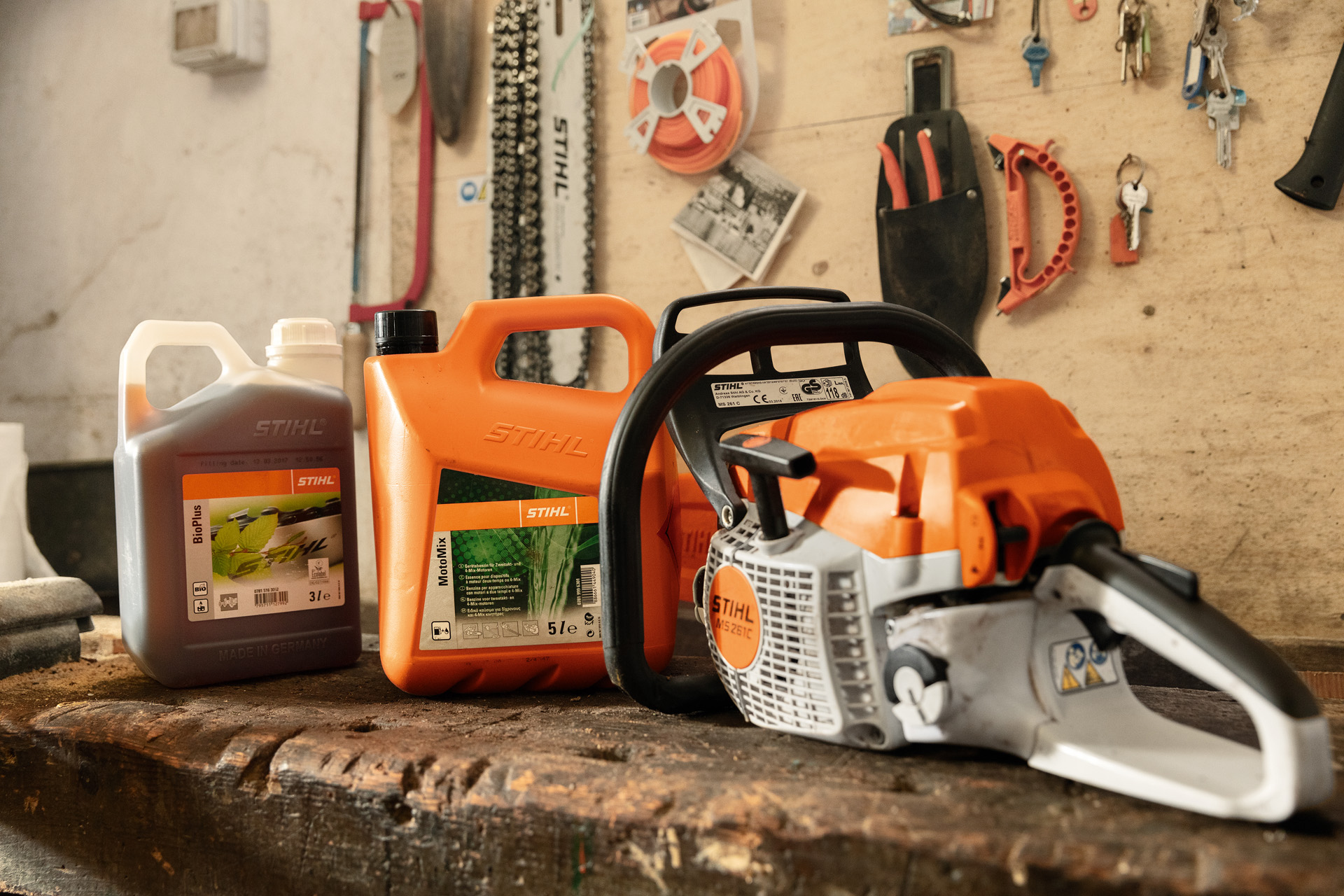 Motosserra MS 261 C-BE com tampa de depósito da STIHL sem ferramenta, numa oficina, junto do MotoMix e BioPlus