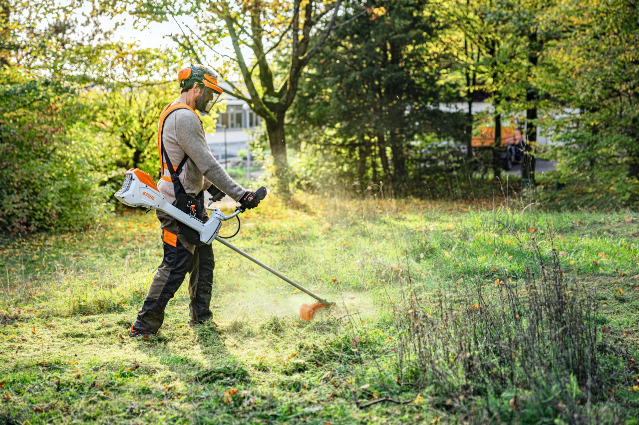 Man caring for the lawn with the STIHL FSA 200 cordless brush cutter with two-handed handle