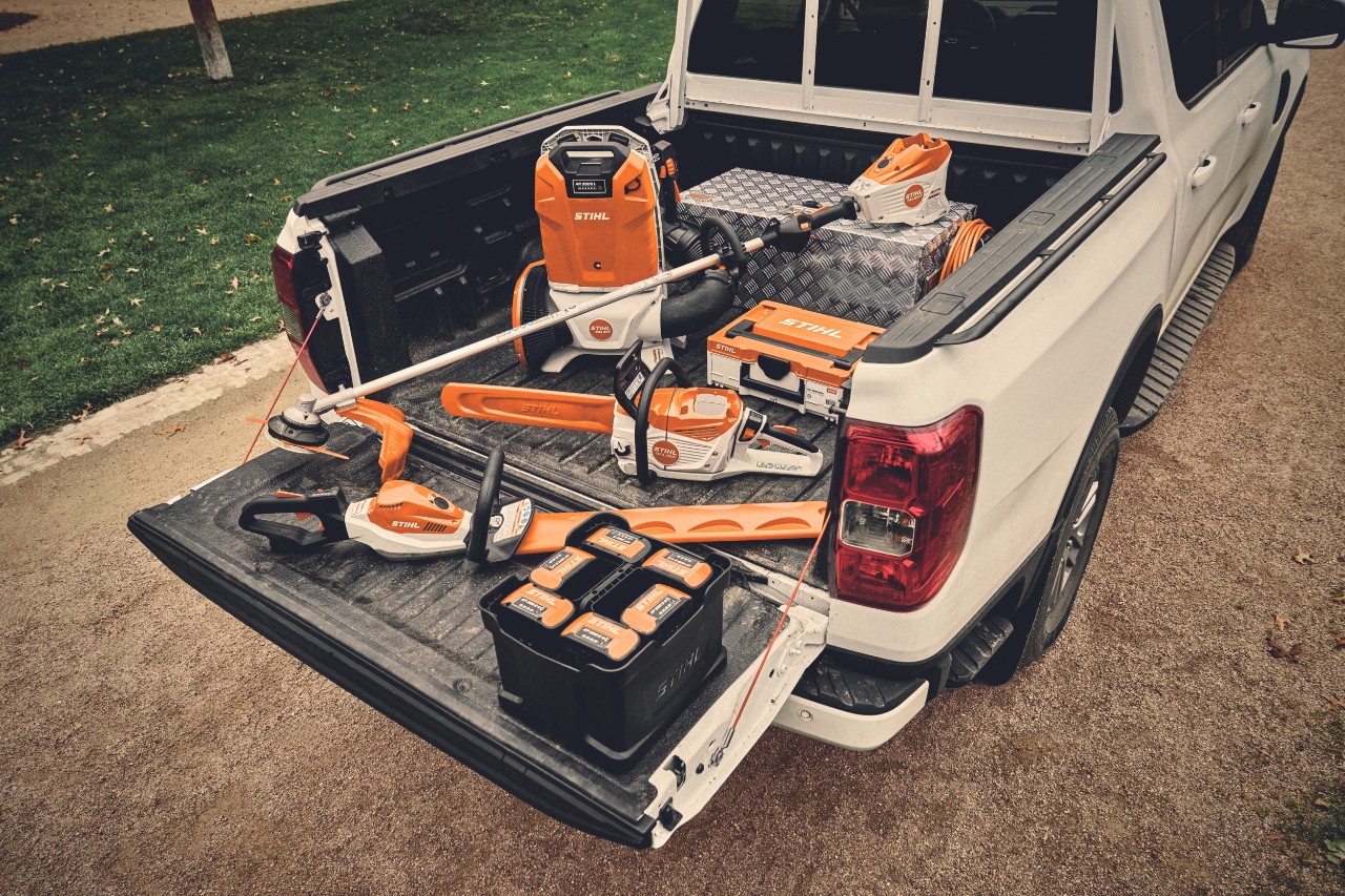 Várias ferramentas a bateria do sistema STIHL AP e as respectivas baterias na área de carga de um veículo