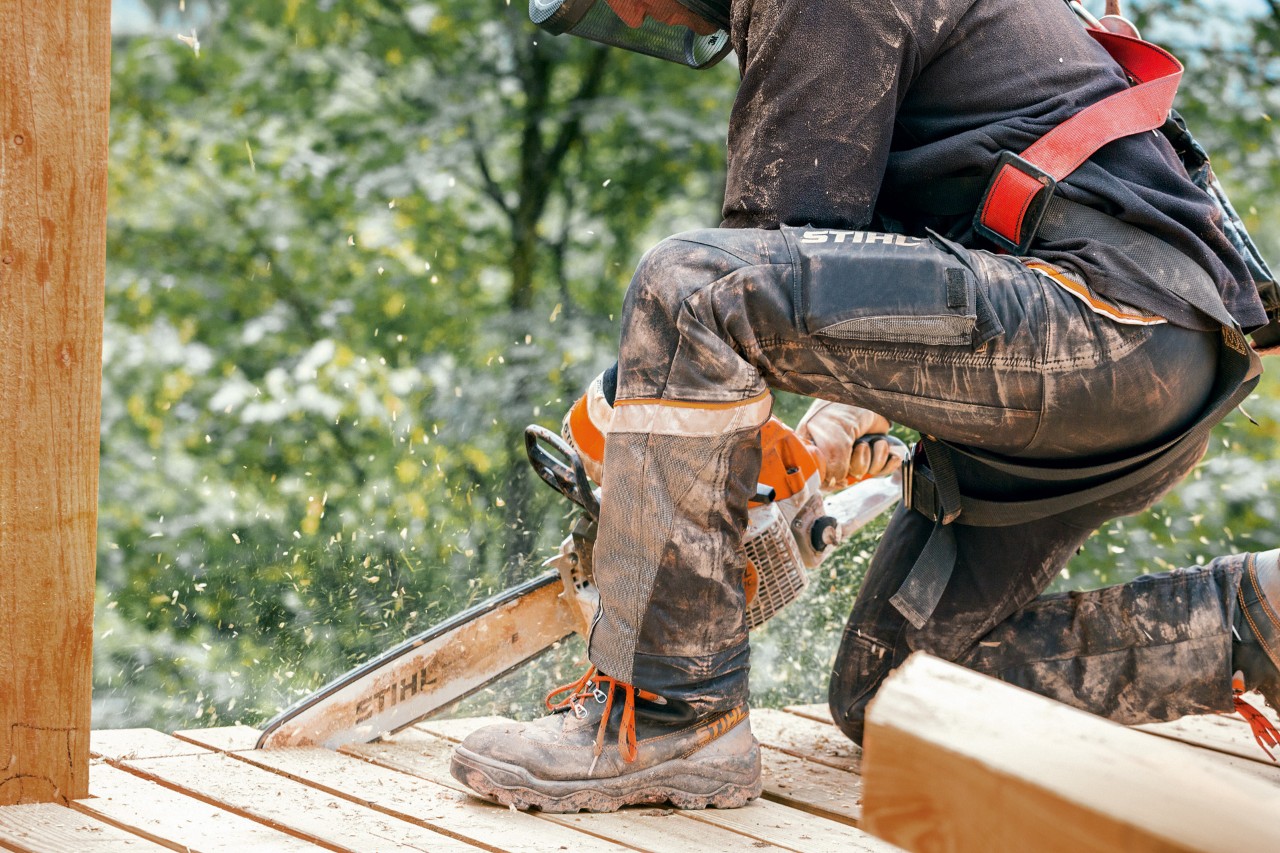 Categorias de proteção de motosserras: uma pessoa com botas de trabalho e calças Advance X-Light da STIHL a serrar 