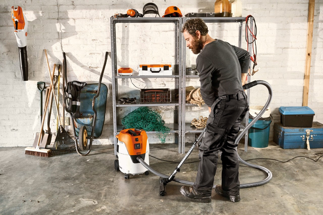 Categorias de extração de pó: homem a aspirar o chão de uma garagem com um aspirador STIHL SE 62 E