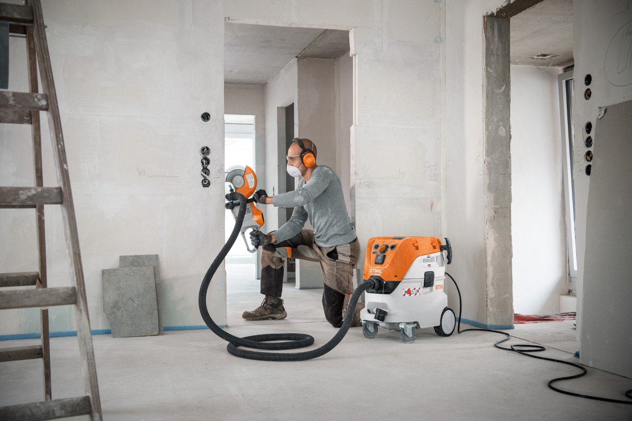 Categorias de extração de pó: um homem a usar um aspirador STIHL SE 133 ME enquanto trabalha com uma cortadora STIHL