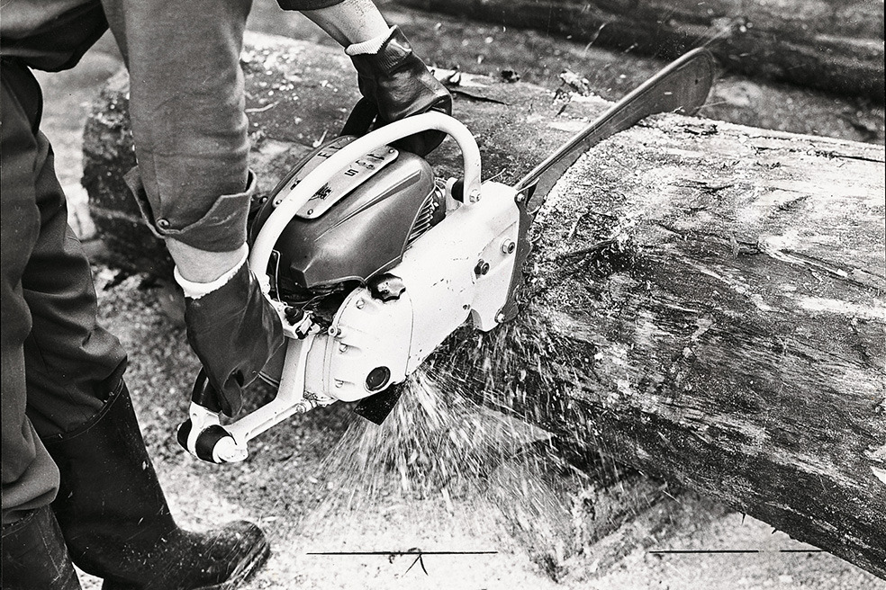 Foto antiga a preto e branco na qual se vê alguém a cortar uma árvore com a motosserra STIHL Contra 