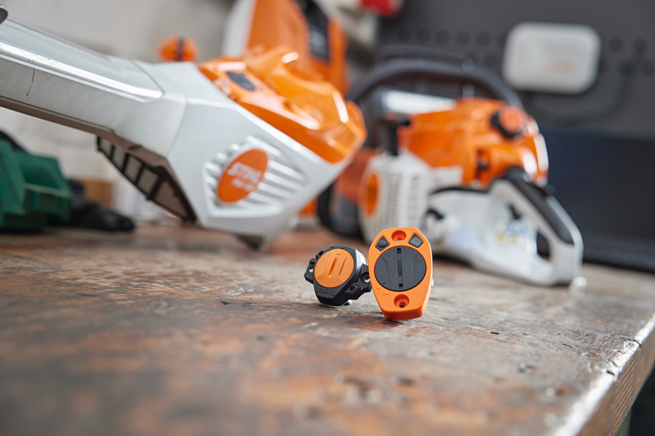 Dois STIHL Smart Connector numa bancada de trabalho. Em segundo plano, podem ver-se diferentes máquinas STIHL.
