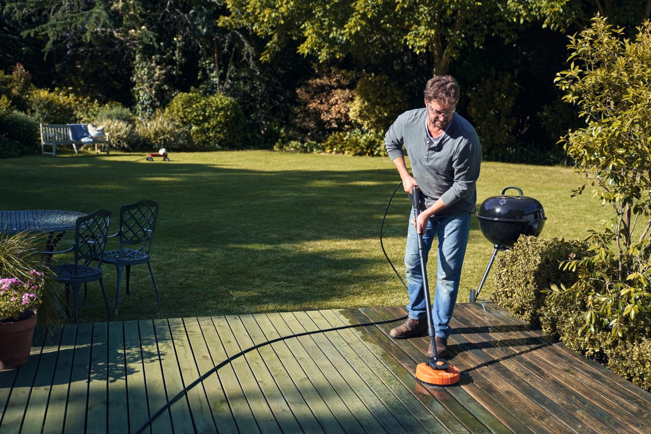 Um homem a limpar o terraço com um dispositivo de limpeza de superfícies STIHL RA 82