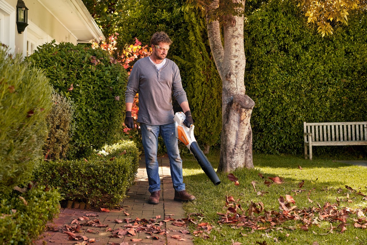 Limpeza das pedras do pavimento: homem a eliminar folhas do pavimento com um soprador de mão a bateria STIHL BGA 57