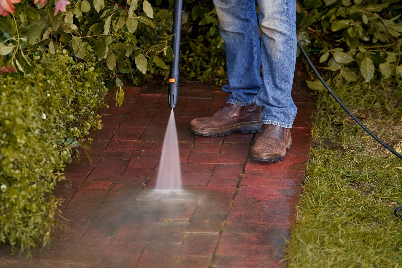 Limpeza de pedras do pavimento no espaço verde com uma máquina de limpeza de alta pressão STIHL RE 110