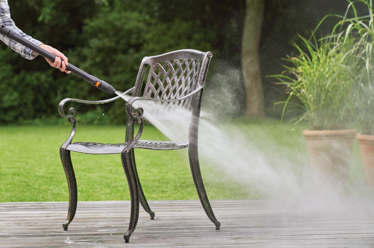 Uma cadeira de metal para jardins a ser limpa com um jato de água da máquina de limpeza de alta pressão STIHL RE 130 Plus