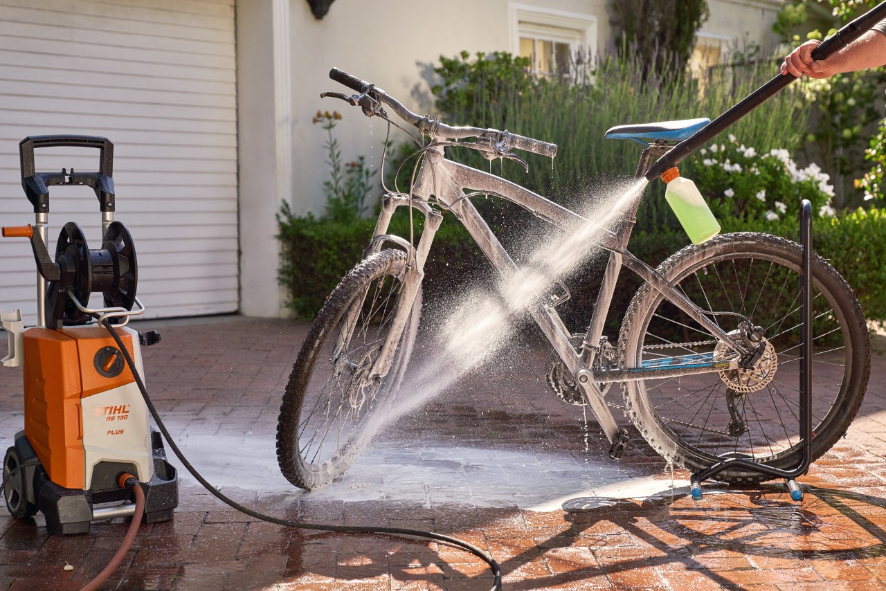 Uma bicicleta a ser limpa com uma lavadora de alta pressão STIHL RE 130 plus com uma boquilha de espuma e champô auto
