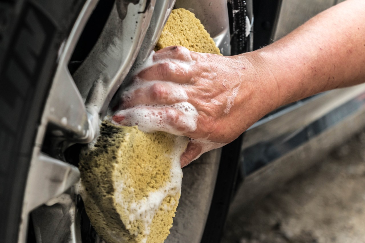 Imagem ampliada de jantes de carro a serem limpas com uma esponja
