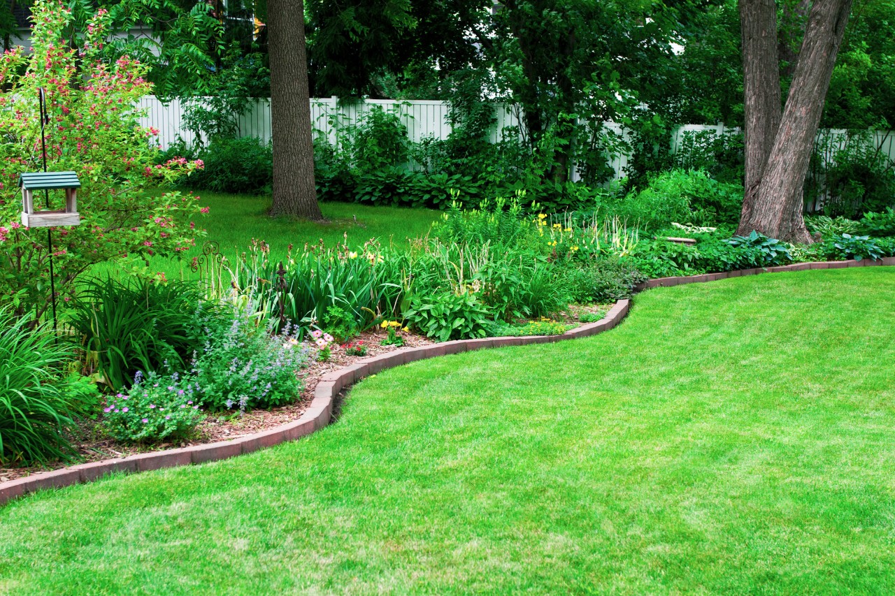 Canteiro de jardim com borda de bricolage feita de pedras num relvado verde