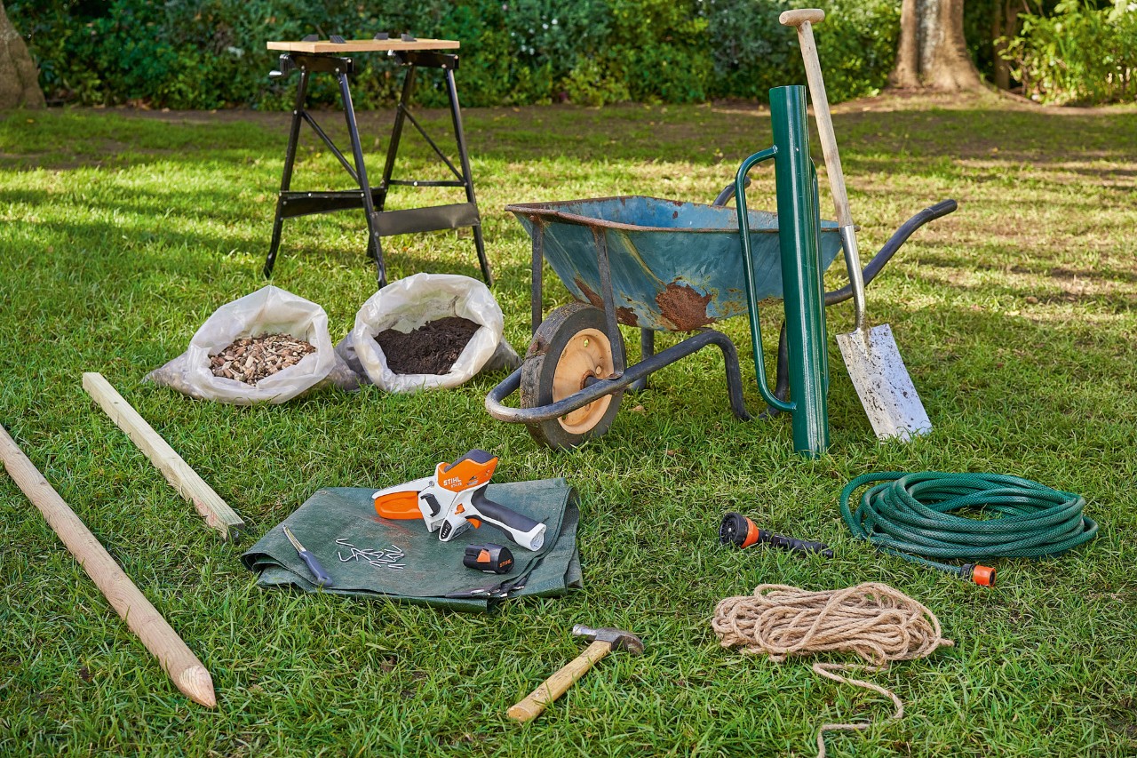 Material de trabalho para plantar árvores, incluindo a minipodadora de corrente a bateria STIHL GTA 26, sobre o relvado
