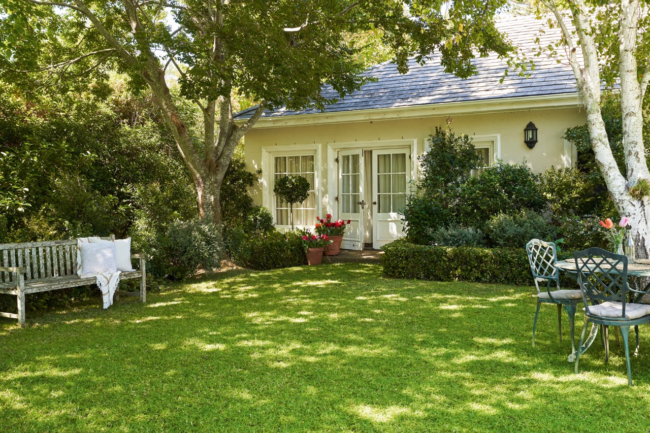 Espaço verde com um relvado verde e saudável depois da aplicação de cal com casa em segundo plano