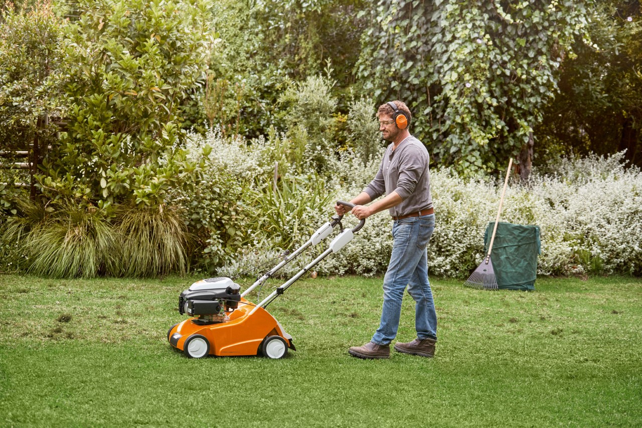 Homem a escarificar um relvado verde com um escarificador STIHL RL 540 – como escarificar relvado