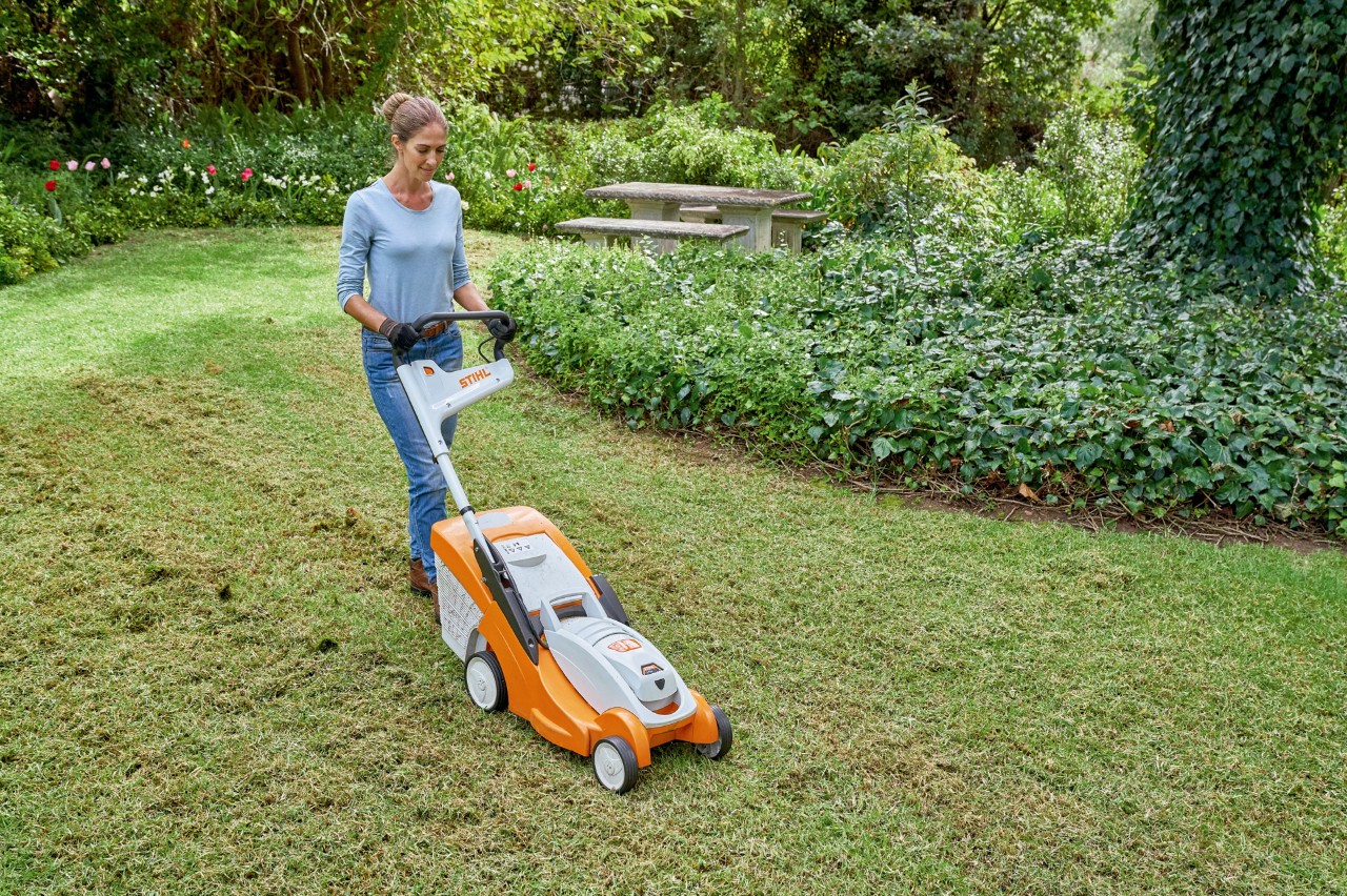 Uma mulher a cortar o relvado com um corta-relva a bateria STIHL RMA 339 C para o preparar para a renovação