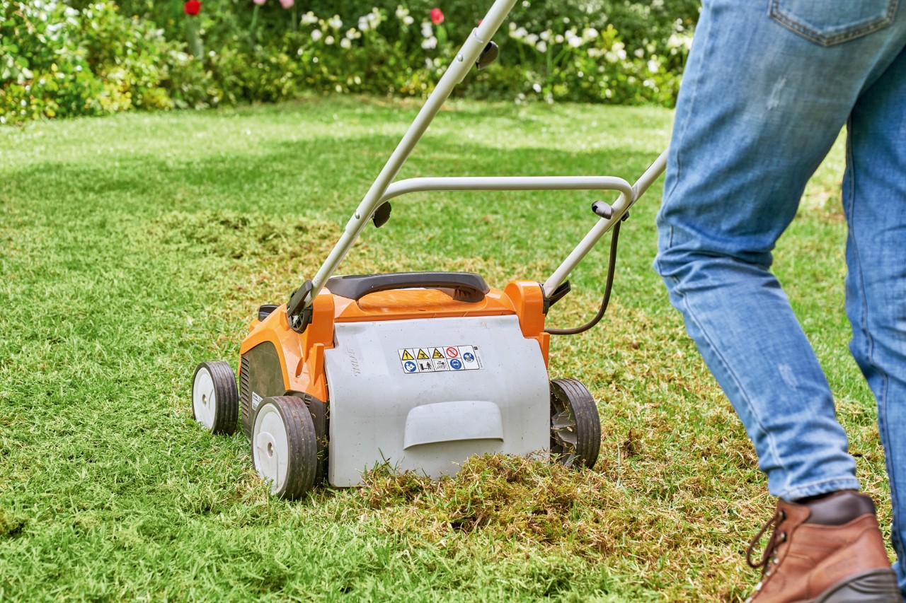 Alguém a escarificar um relvado com um escarificador elétrico STIHL RLA 240 para o preparar para o rejuvenescimento