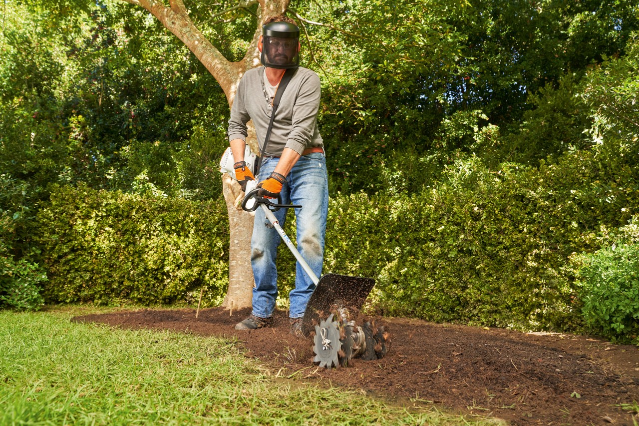 Um homem trabalha o húmus no solo com um sistema combinado STIHL KM 56 RC-E