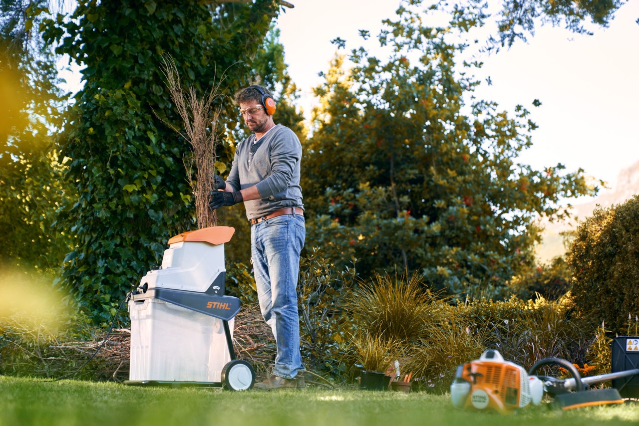 Homem com proteção auditiva a triturar ramos antes da compostagem com um biotriturador elétrico STIHL GHE 140