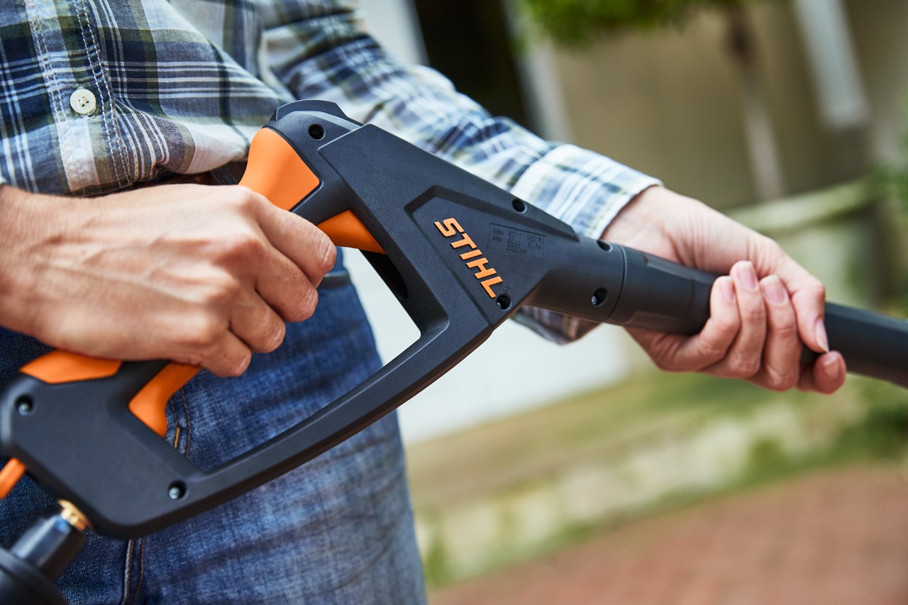 Uma pessoa aciona a pistola de pulverização com a lavadora de alta pressão STIHL RE 130 PLUS desligada para a testar