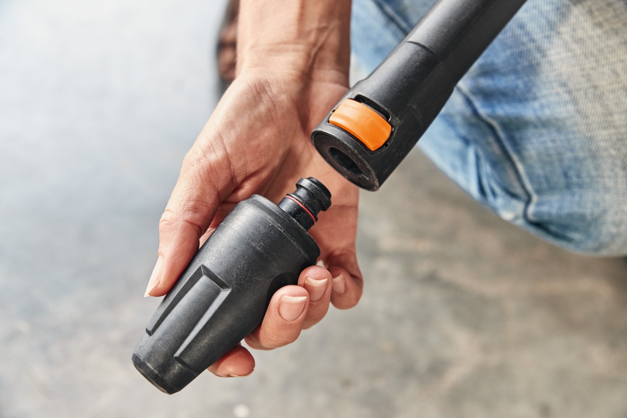  Uma pessoa monta um acessório na lavadora de alta pressão STIHL RE 130 PLUS para a utilizar