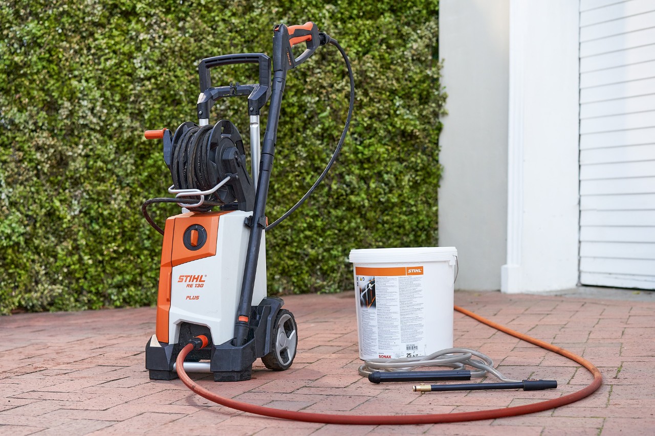 Lavadora de alta pressão STIHL RE 130 PLUS e areia calibrada SB 90 para injeção de areia húmida à frente de uma garagem 