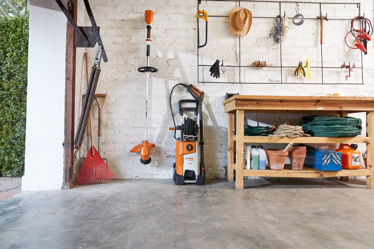 Máquina de lavar de alta pressão STIHL RE 130 PLUS numa garagem com outras máquinas e ferramentas
