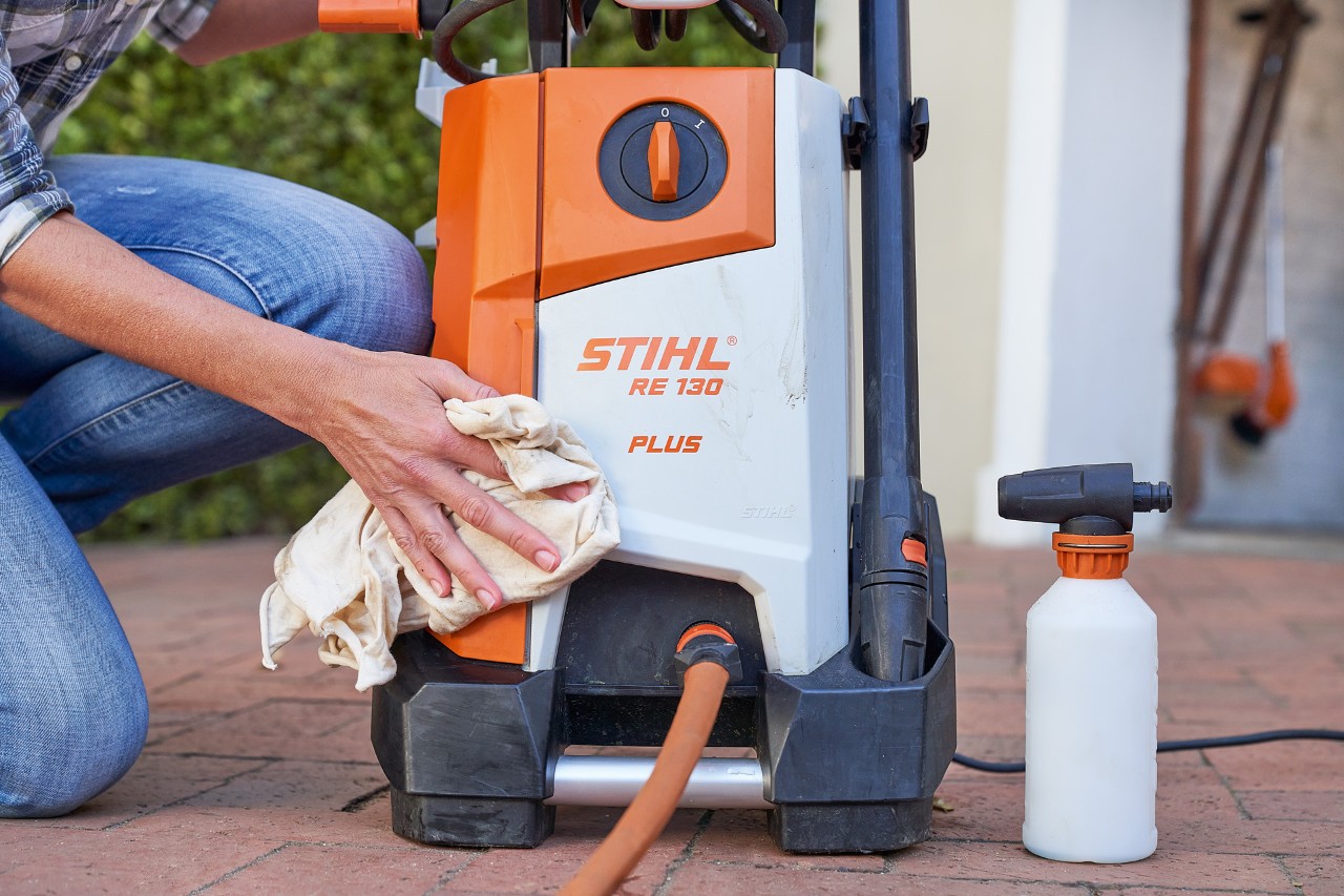 Uma mulher faz a manutenção da lavadora de alta pressão STIHL RE 130 PLUS com um agente anticongelante