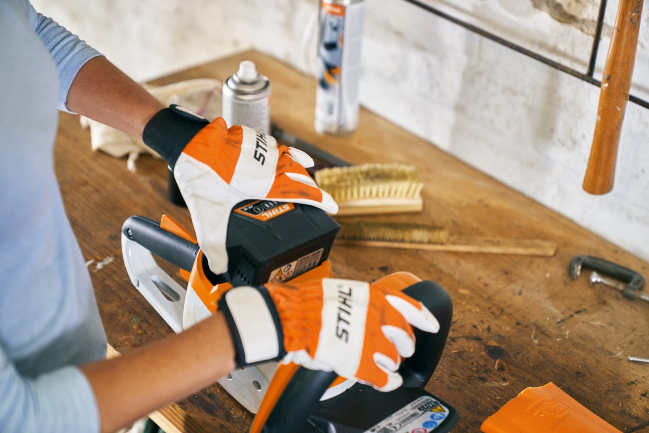 Pessoa com luvas a trabalhar no corta-sebes a bateria STIHL HSA 56