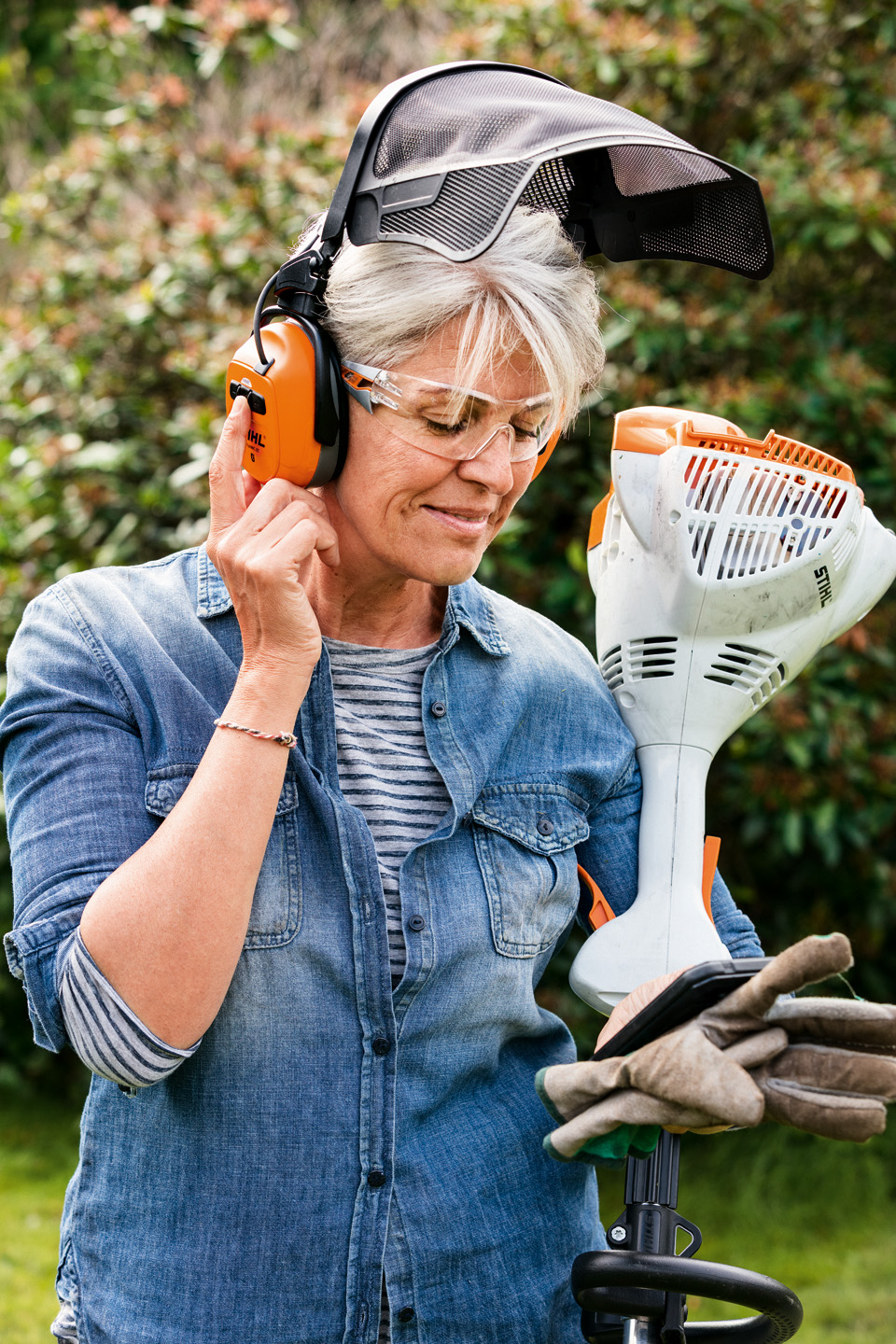 Mulher com proteção combinada facial e auditiva STIHL DYNAMIC BT-N a segurar motorroçadora a gasolina STIHL FS 56 R