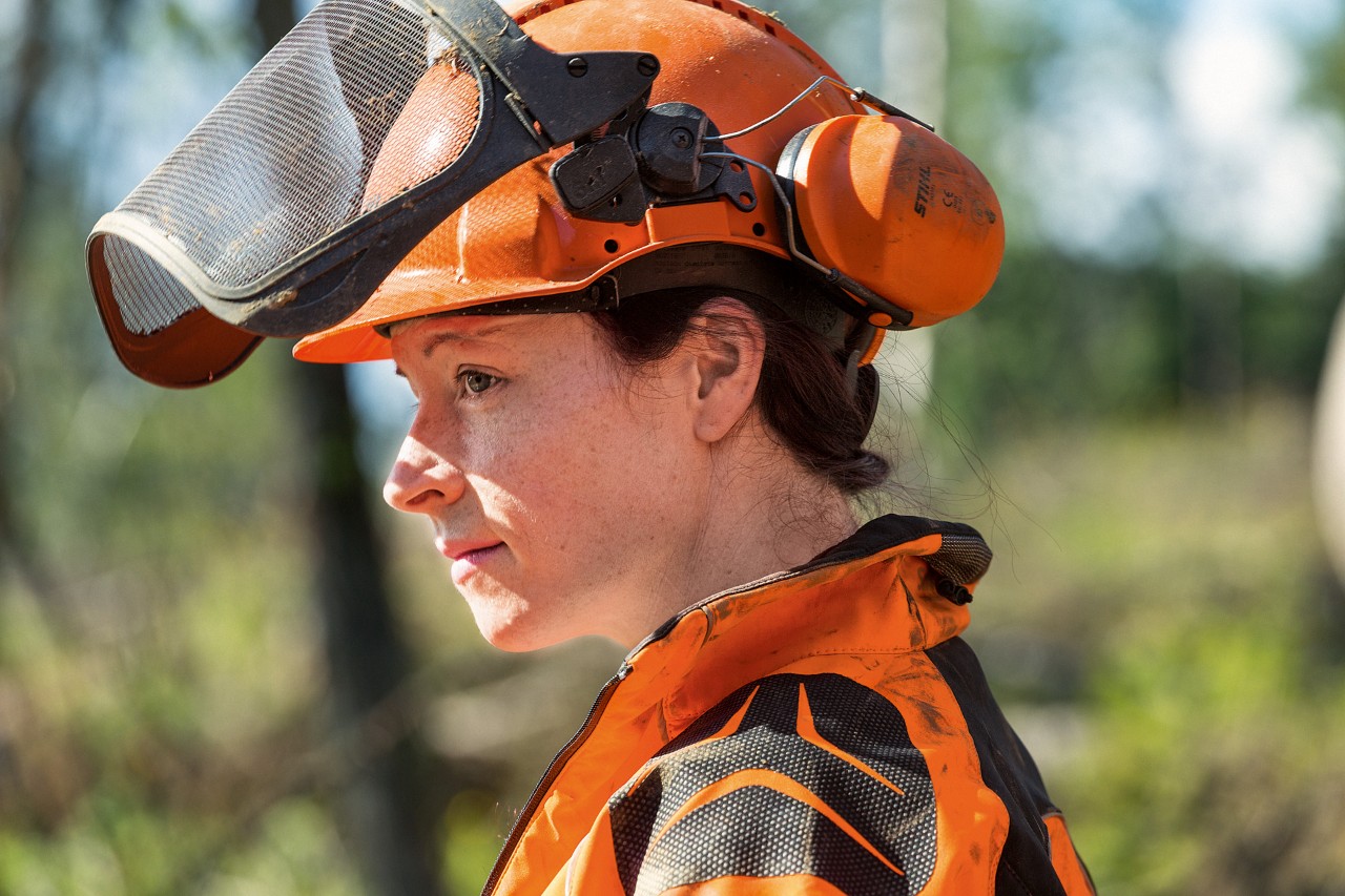 Mulher a usar conjunto de capacete STIHL, com proteção facial, proteção auditiva e capacete - kit de EPI para motosserra 