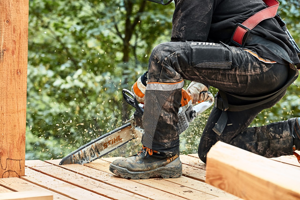 Plataforma de tábuas de madeira é cortada por alguém com uma motosserra STIHL MS 261 e a usar calças de proteção STIHL ADVANCE X LIGHT