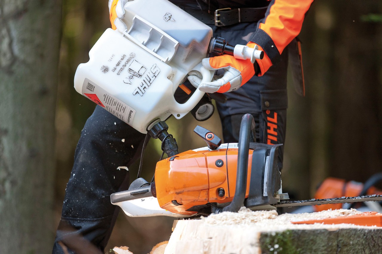 Uma motosserra STIHL MS 441 a ser abastecida a partir de um jerrican duplo com uma mistura de gasolina para motosserra