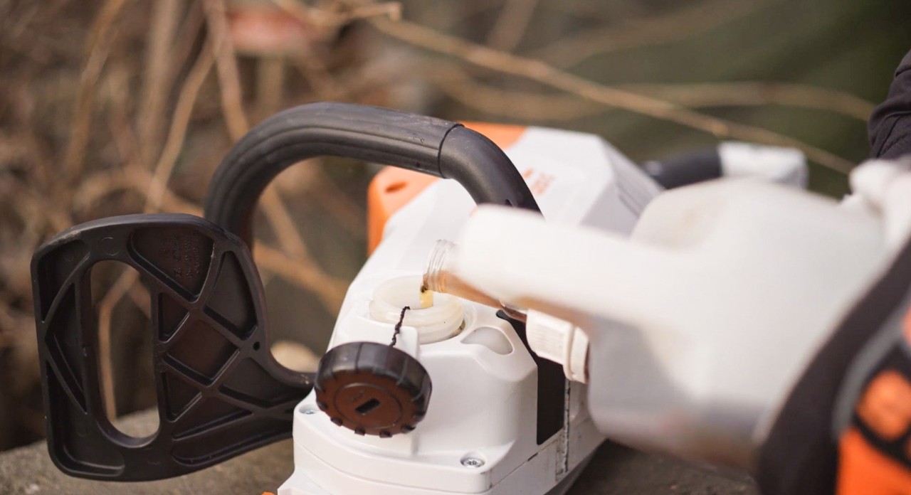 Uma motosserra a bateria STIHL MSA 120 a ser enchida com óleo de correntes