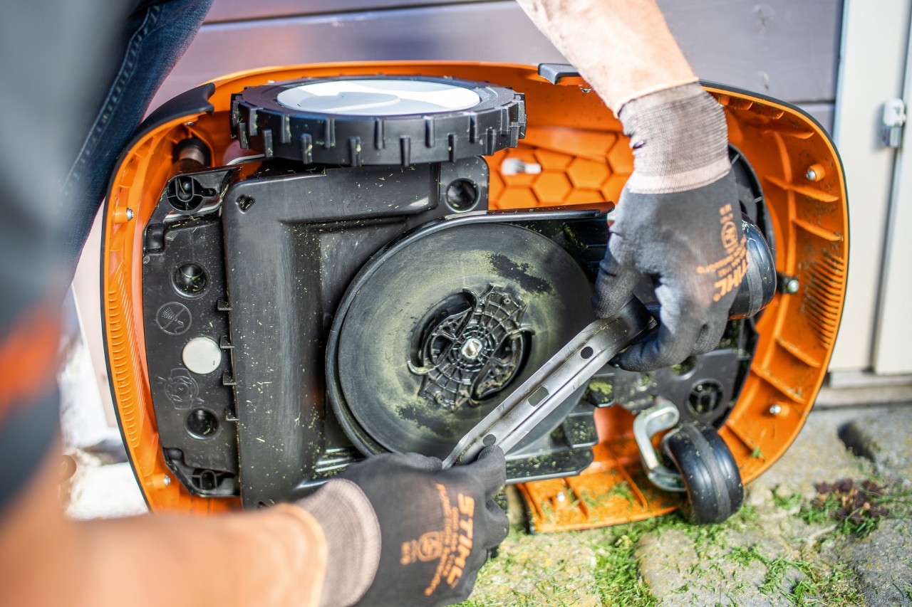 Lâmina de corte a ser removida de um robot corta-relva STIHL iMOW® 422 por uma pessoa de luvas