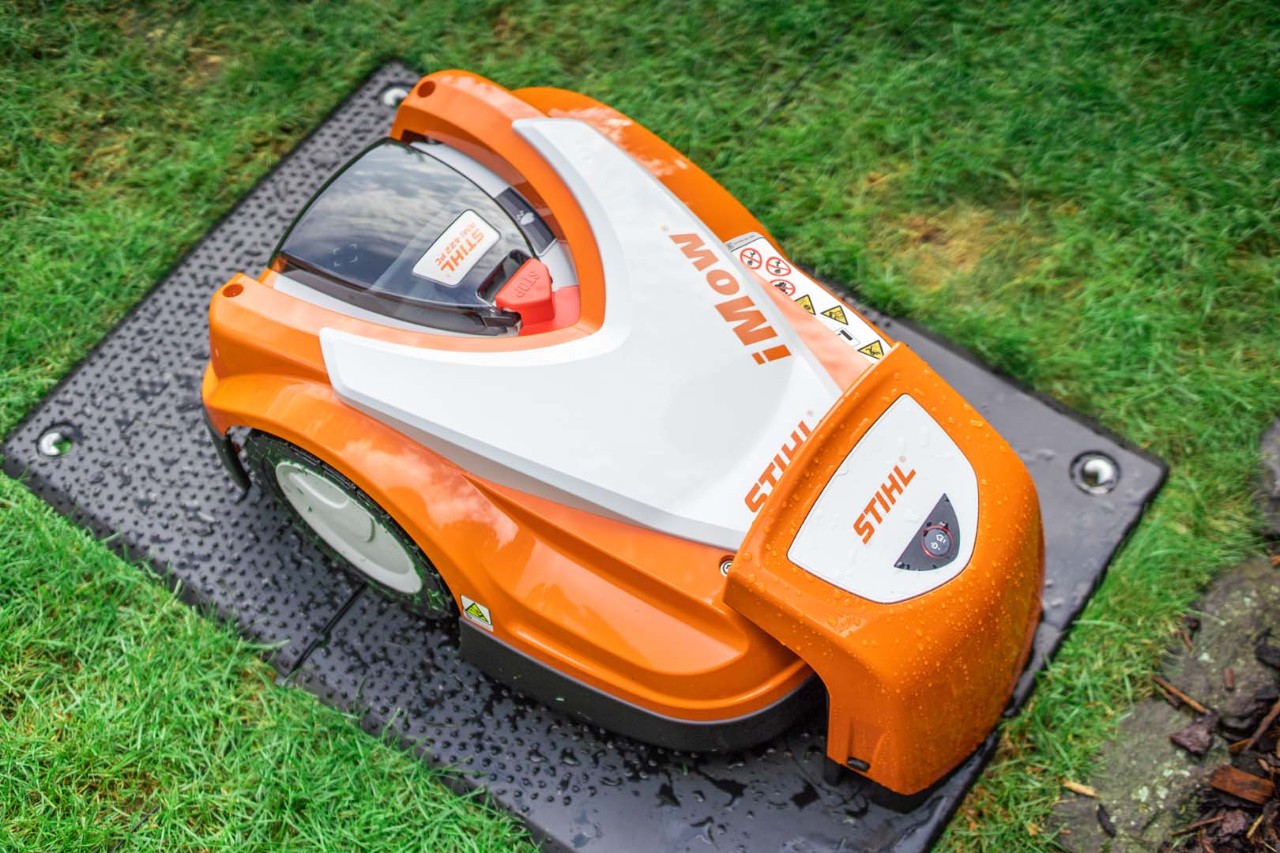 Um robot corta-relva STIHL iMOW® 422 na respetiva estação de carga num relvado