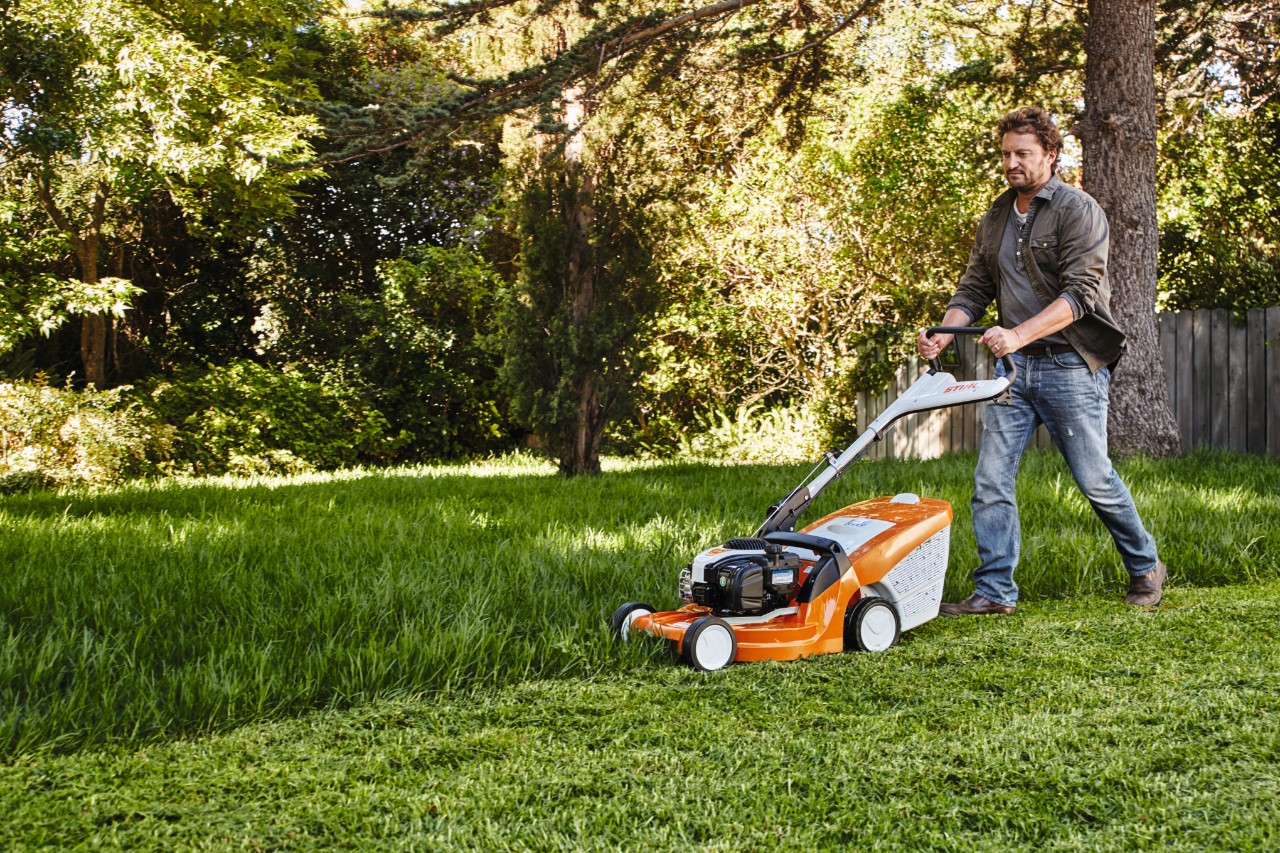 Um homem corta a relva num jardim com um corta-relva STIHL 