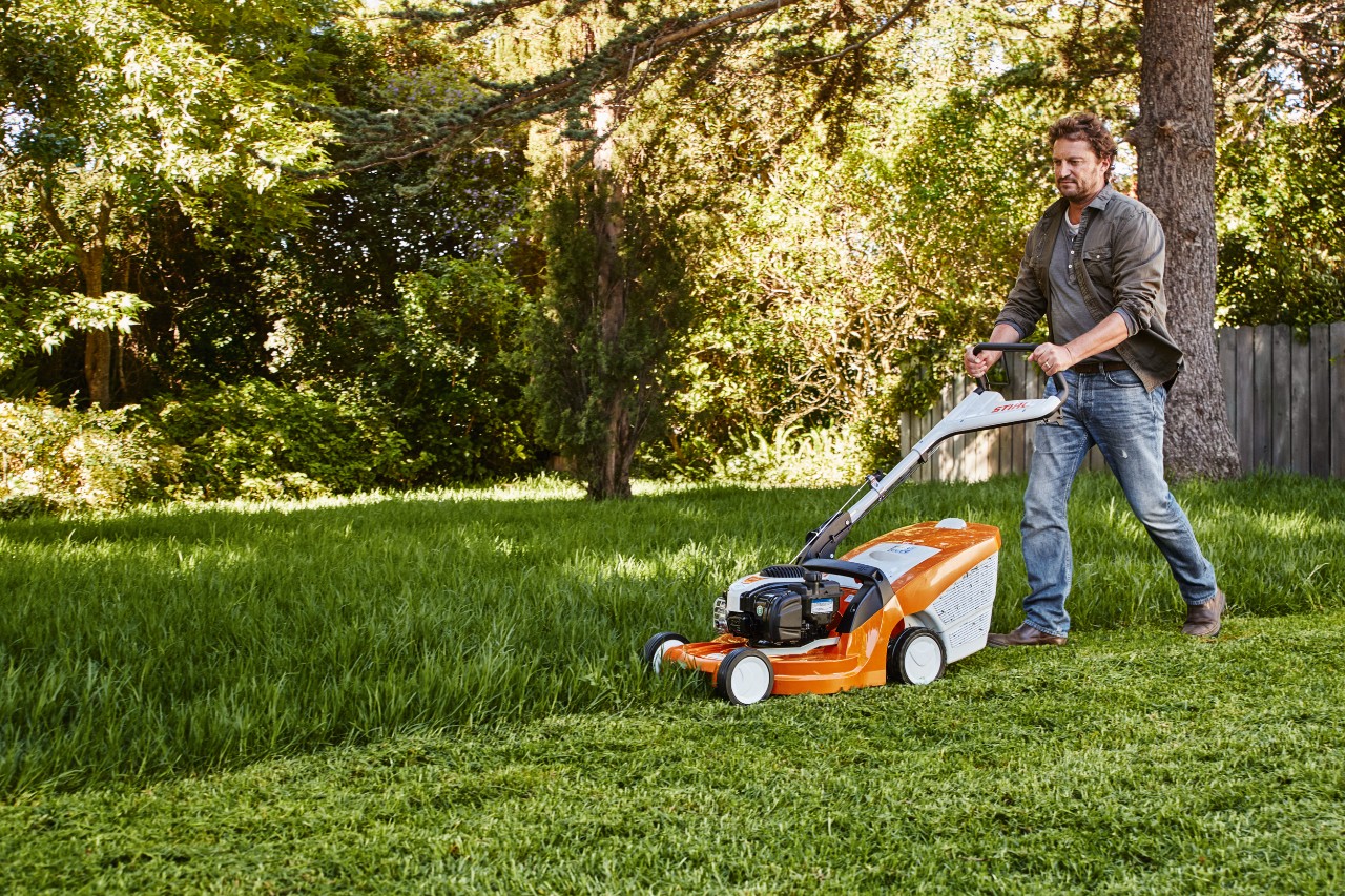 Um homem corta a relva num jardim com um corta-relva STIHL 