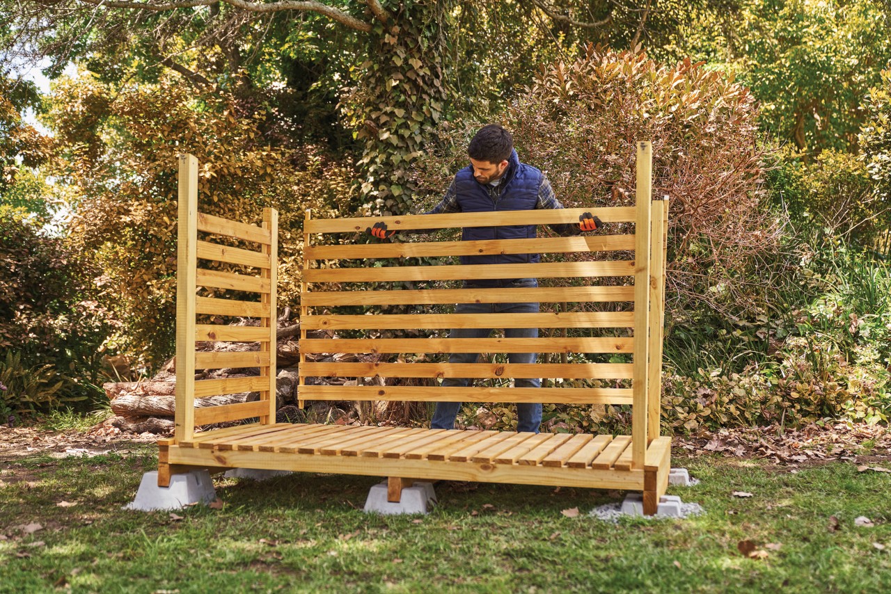 Como construir um lenheiro: um homem a instalar o painel da parede traseira