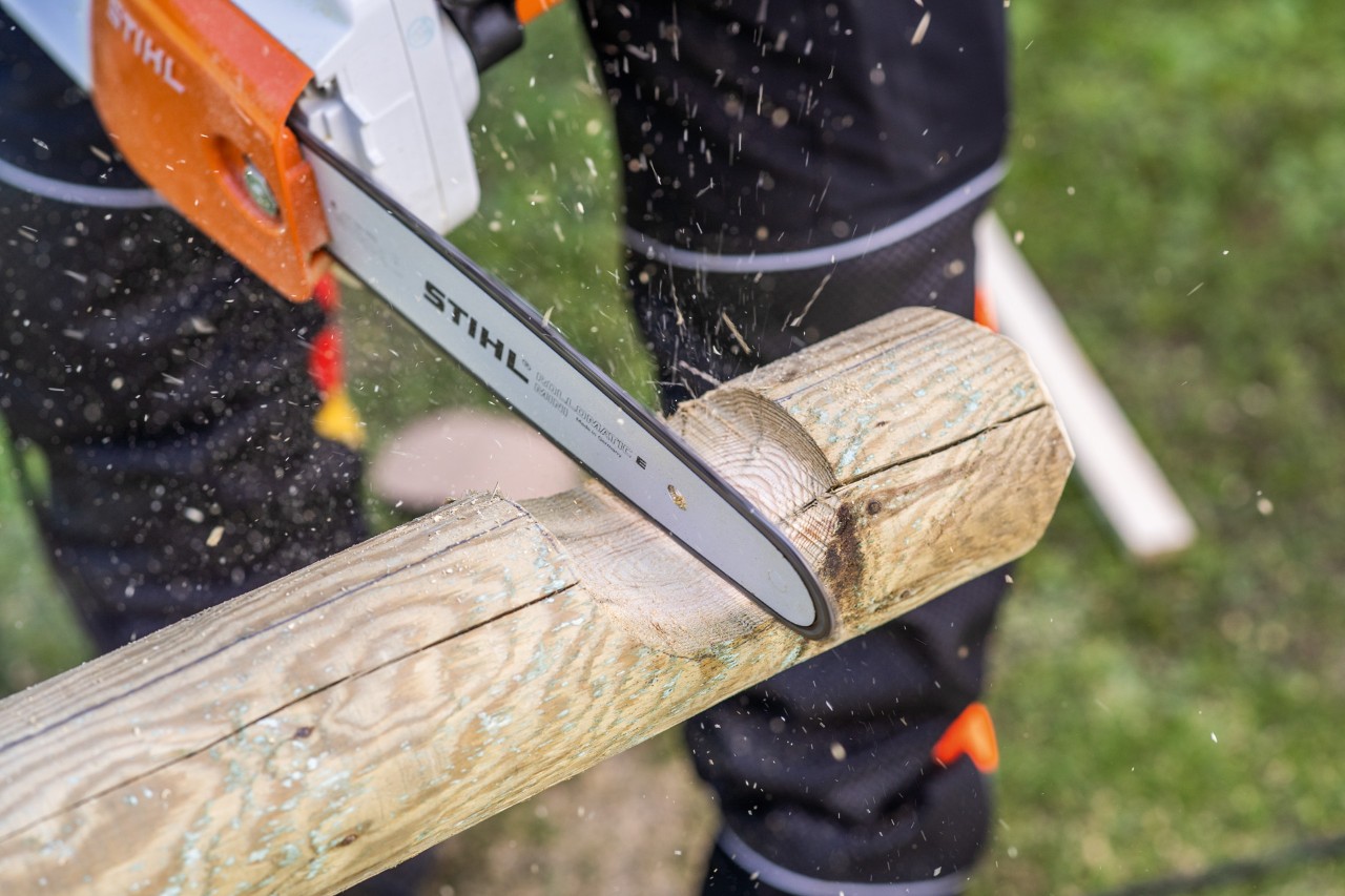 Um entalhe curvo é aberto numa estaca com uma motosserra STIHL. Construir caixa de bricolage para areia.