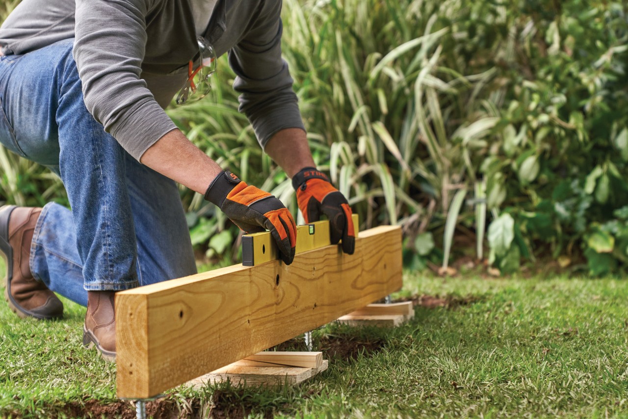 Como construir um abrigo de jardim: uma trave do piso com as buchas metálicas a ser posicionada no devido lugar