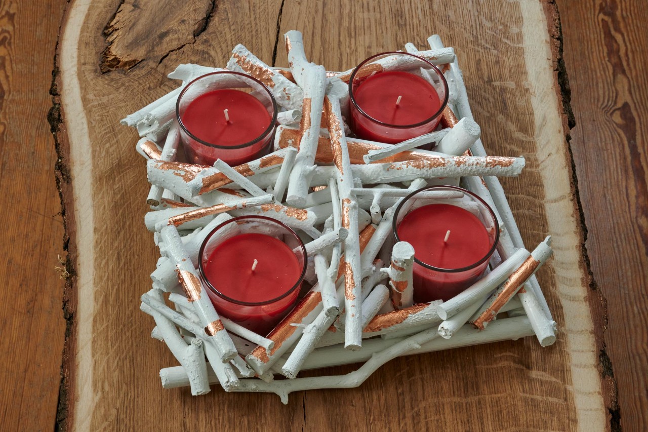 Centro de mesa de Natal de bricolage: um centro de mesa de galhos pronto com quatro velas vermelhas em suportes