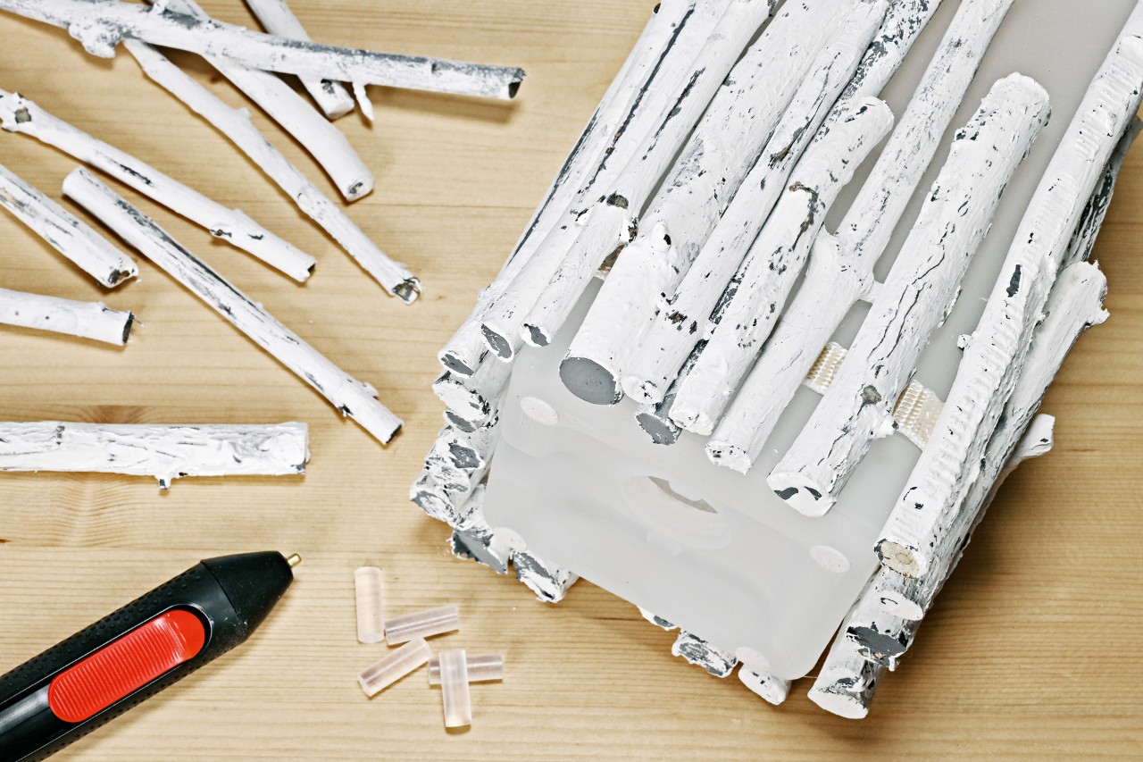 Luminária de mesa de bricolage com galhos: fita com ramos pintados colados a uma luminária com uma pistola de cola