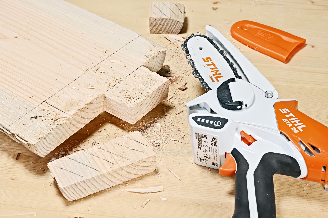 Mesa de apoio: secções a serem cortadas numa tábua de madeira por uma minipodadora de corrente a bateria STIHL GTA 26