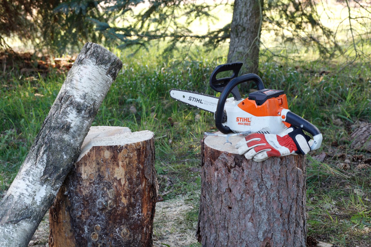 Castiçais de bricolage em madeira: uma motosserra STIHL e luvas de proteção num cepo com outros toros por perto