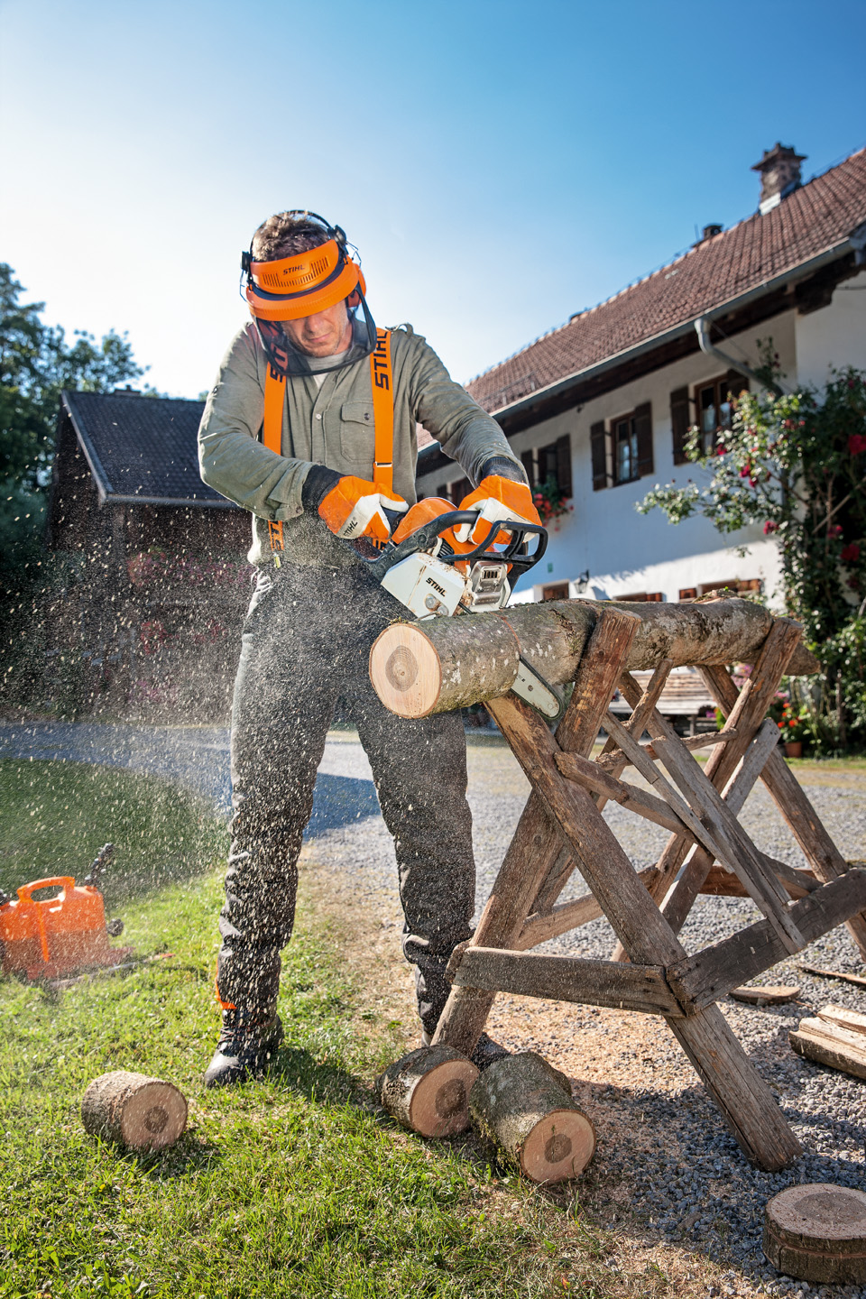 Homem com vestuário de proteção usa motosserra STIHL MS 170 a gasolina para cortar o tronco de uma árvore num cavalete