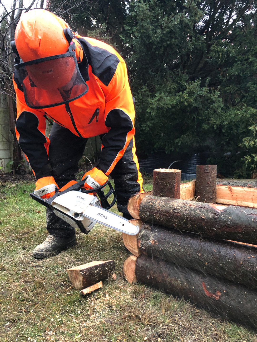 Construir canteiro elevado a partir de toros: homem com equipamento de proteção usa uma motosserra STIHL MS 170