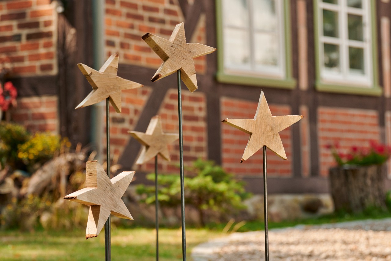 Cinco estrelas de madeira em varetas espetadas no chão à frente de um edifício de tijolo vermelho