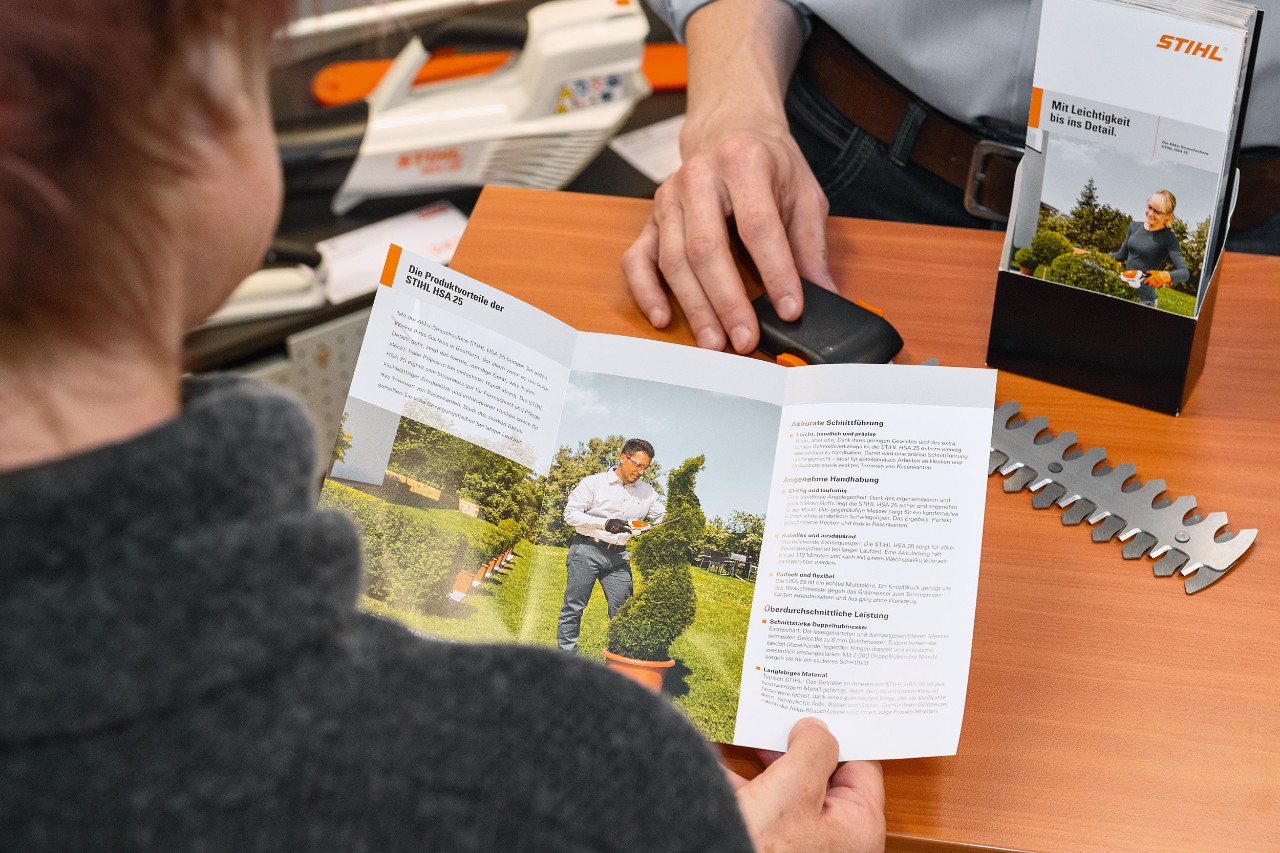 Pessoa a analisar as vantagens do produto STIHL HSA&nbsp;25 numa brochura