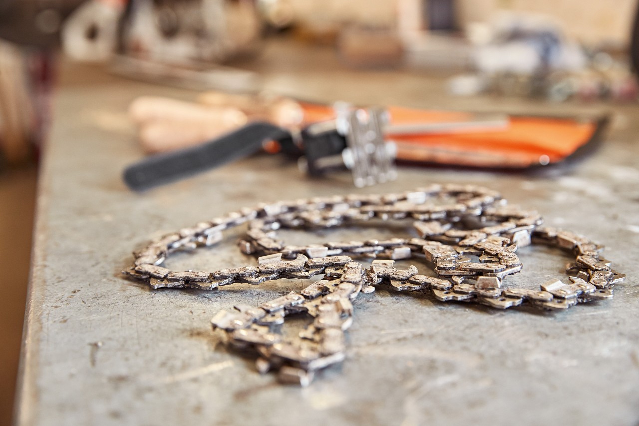Uma corrente de motosserra STIHL ao lado de uma ferramenta sobre uma bancada de trabalho